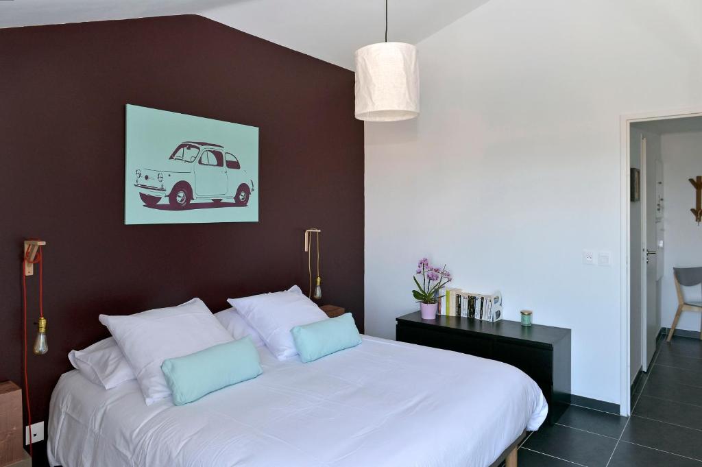a bedroom with a white bed with a brown wall at Quintessens in Marseille