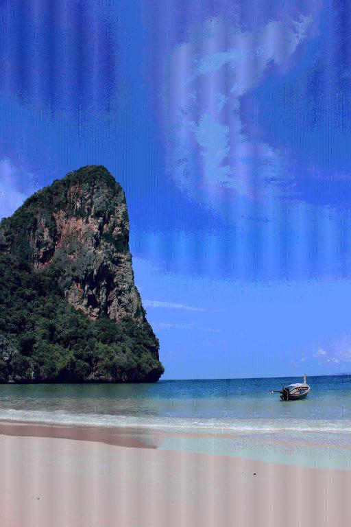 a boat on the beach with a rock in the water at Railay Village Resort in Railay Beach