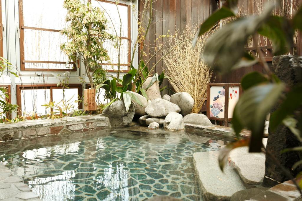 a pool in the middle of a room with plants at Dormy Inn Kagoshima in Kagoshima