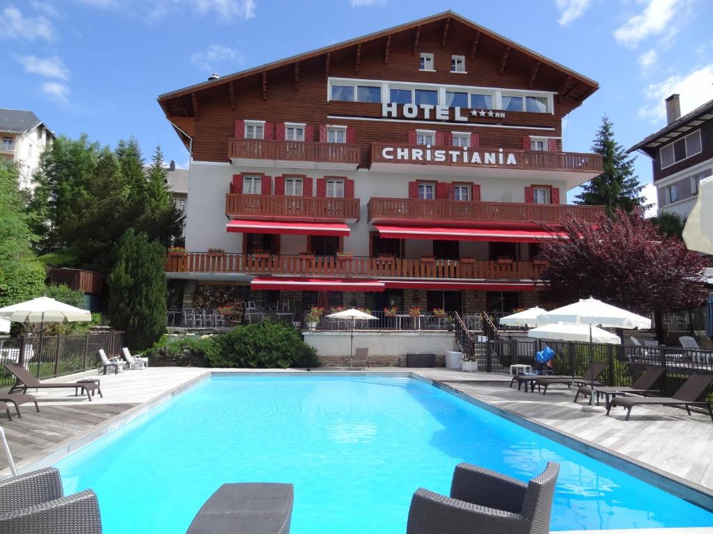 un hôtel avec une piscine en face d'un bâtiment dans l'établissement Hotel Christiania, à Villard-de-Lans