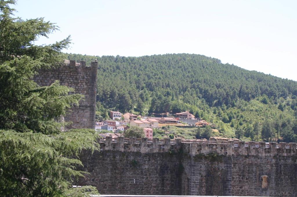 una gran pared de piedra con una ciudad en el fondo en Hostal El Castillo en Arenas de San Pedro