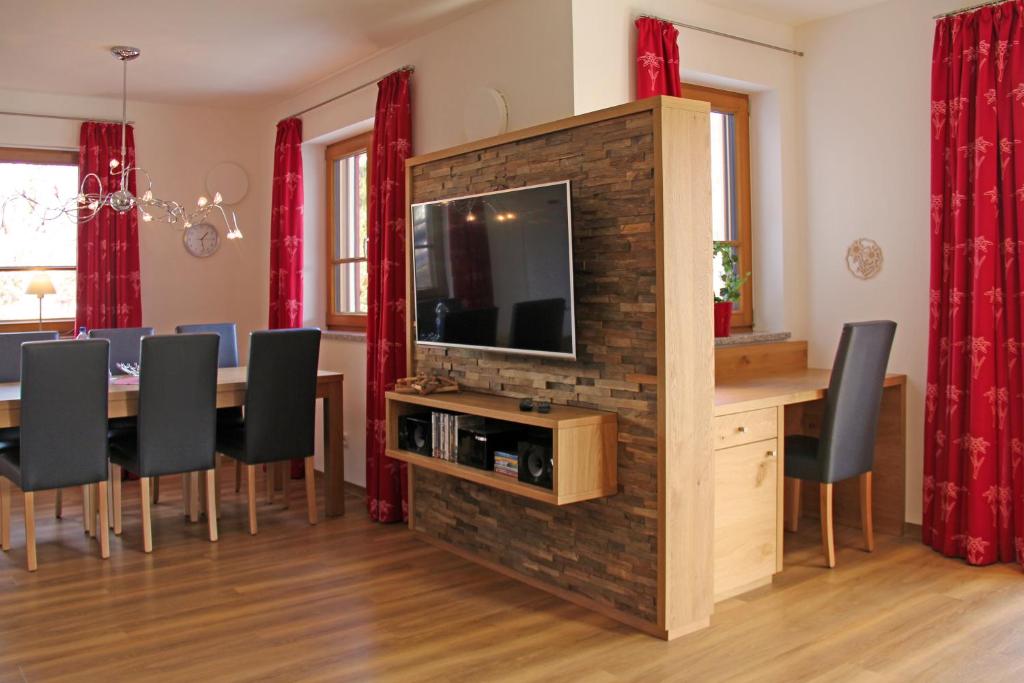 a dining room with a table and a television on a brick wall at Landhaus Stillachaue in Oberstdorf