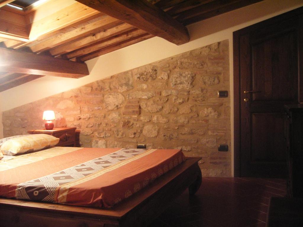 ein Schlafzimmer mit einem Bett und einer Steinmauer in der Unterkunft Le Pergoline B&B in Casciana Terme