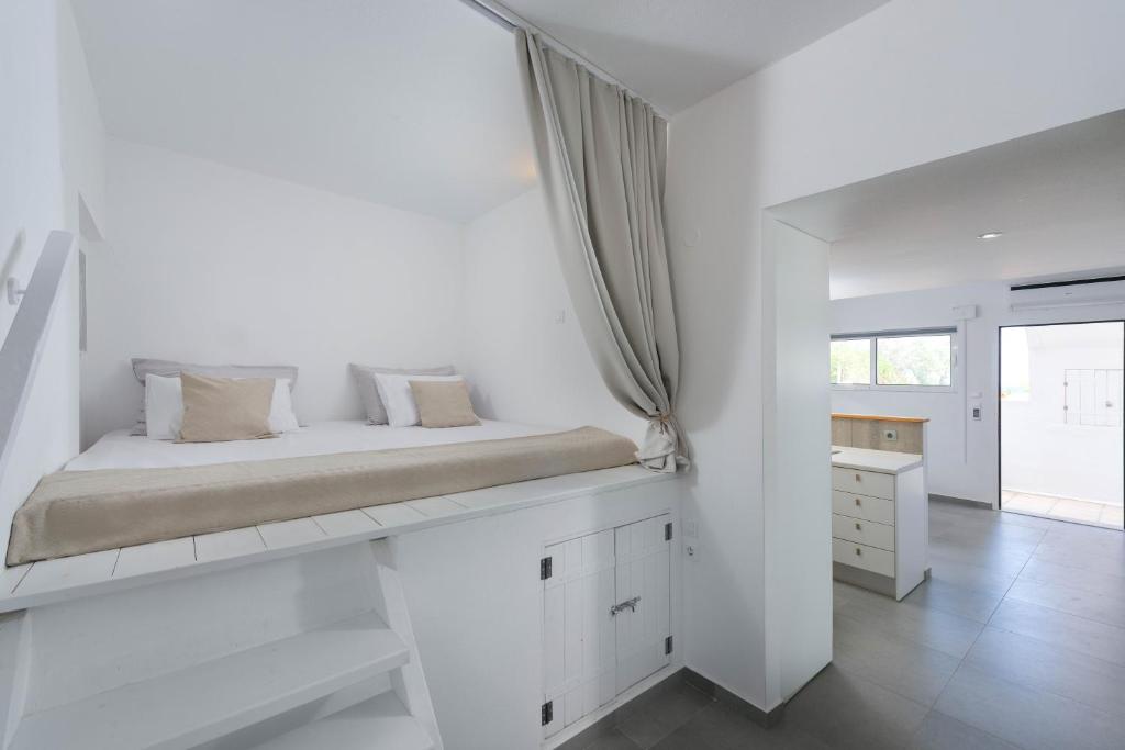 a white bedroom with a bed and a window at Vamare Beachfront House in Gennadi