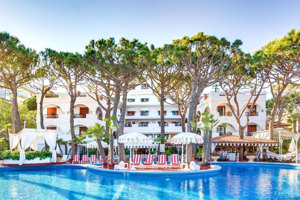 un complexe avec une piscine bordée de chaises et d'arbres dans l'établissement Park Hotel Agora, à Lido di Jesolo