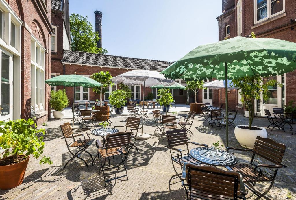 un patio avec des tables, des chaises et des parasols dans l'établissement Hotel Arena, à Amsterdam