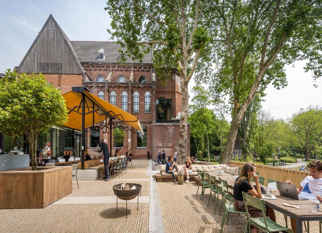 personnes assises à des tables devant un bâtiment dans l'établissement Hotel Arena, à Amsterdam