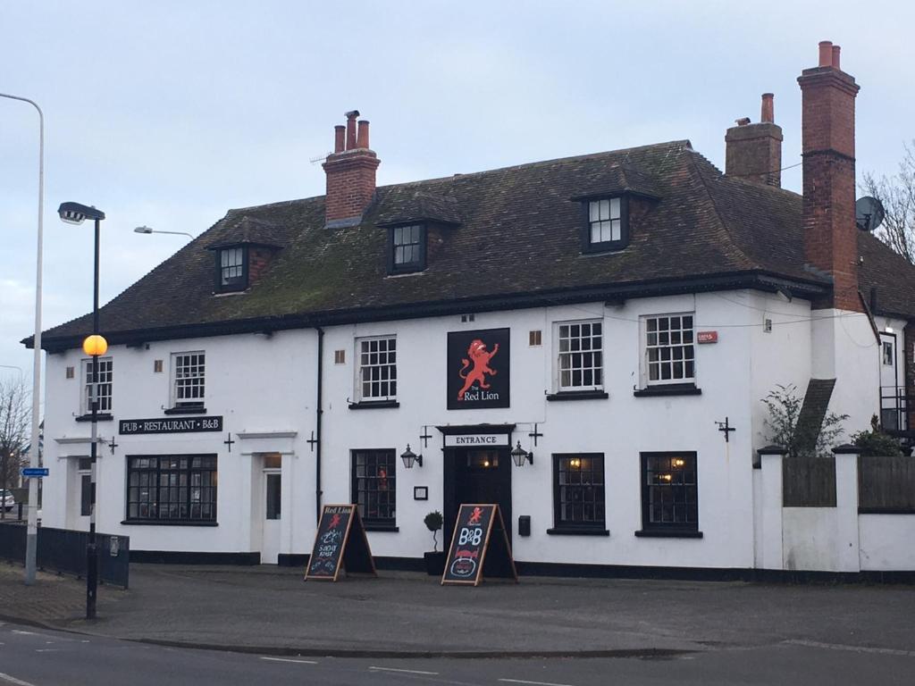 un bâtiment blanc avec des panneaux devant lui dans l'établissement The Red Lion, à Hythe