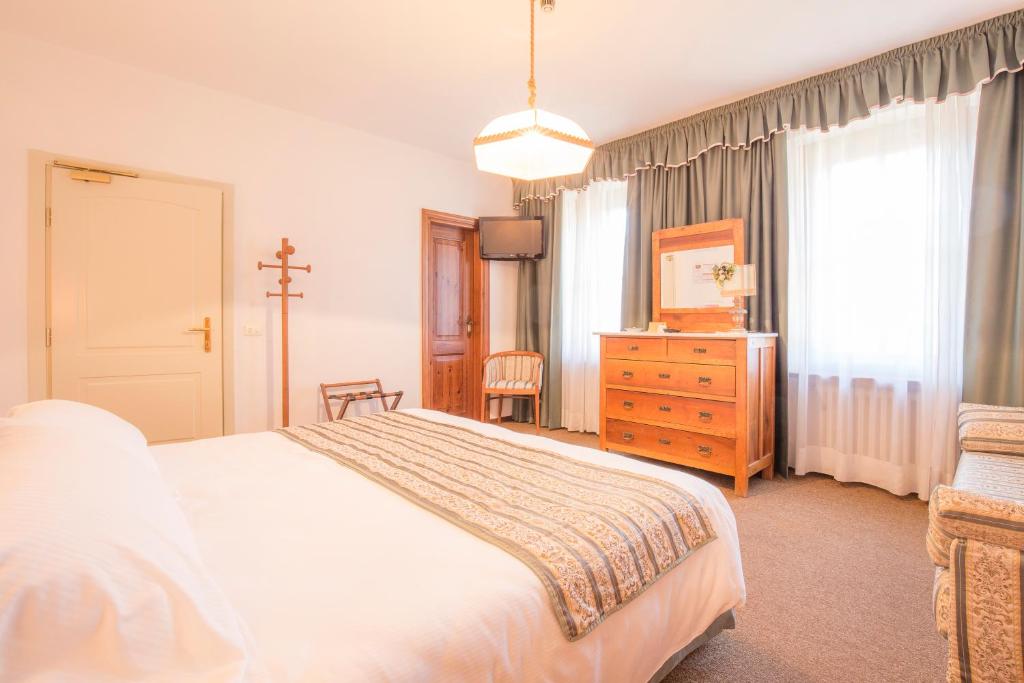 sypialnia z łóżkiem, komodą i oknem w obiekcie Hotel Villa Trieste w mieście San Vito di Cadore