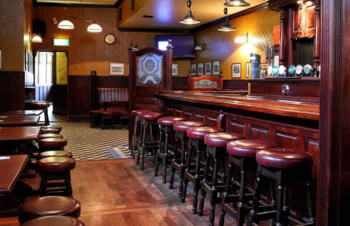 um bar com uma fila de bancos num restaurante em Kennedys B&B Drumcondra em Dublin