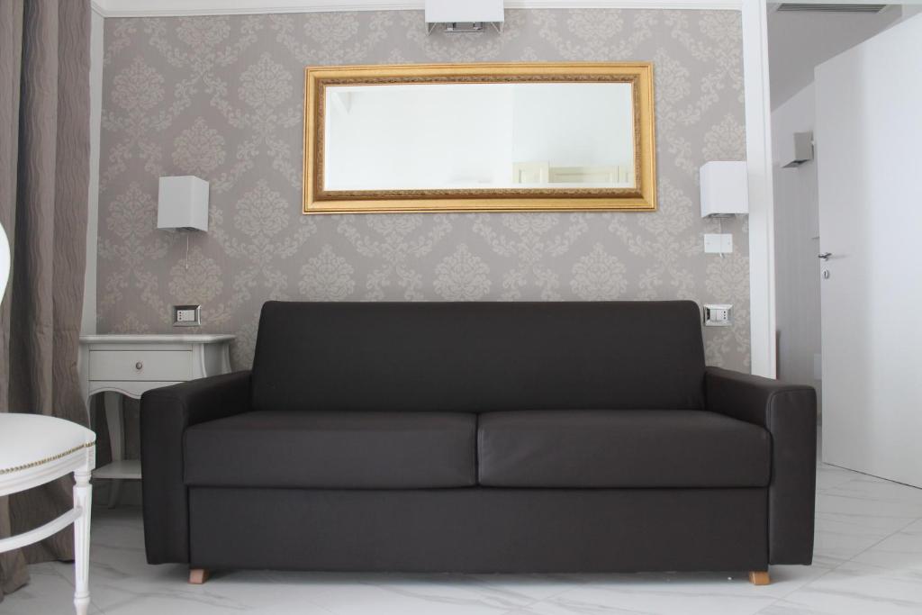 a living room with a black couch and a mirror at Hotel Residence Villa Del Mare in Rimini