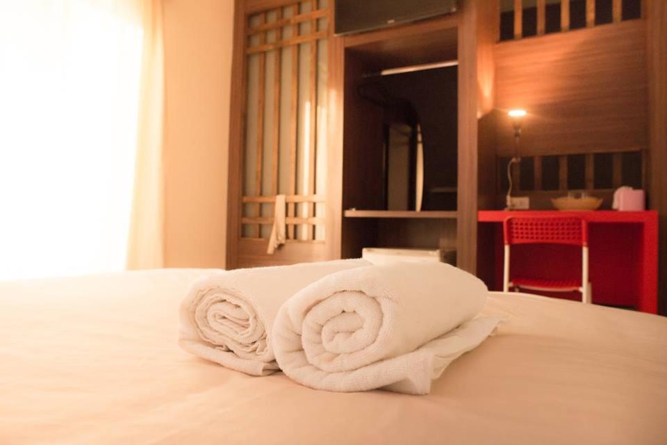 una pila de toallas sentadas encima de una cama en T.U.B. Mansion, en Nonthaburi