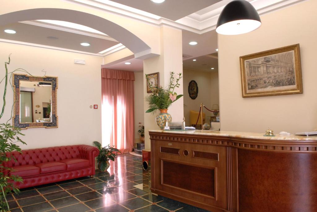 una sala de espera con un sofá rojo y un espejo en Hotel Paradiso Delle Madonie, en Castelbuono