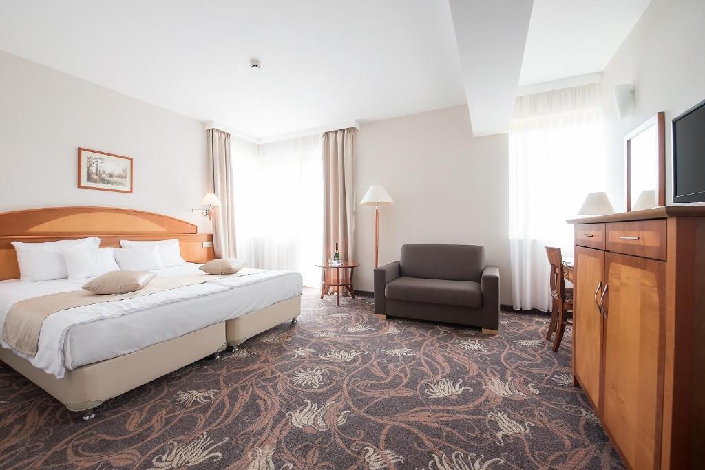 een hotelkamer met een bed en een stoel bij Vitalmed Hotel Sárvár in Sárvár