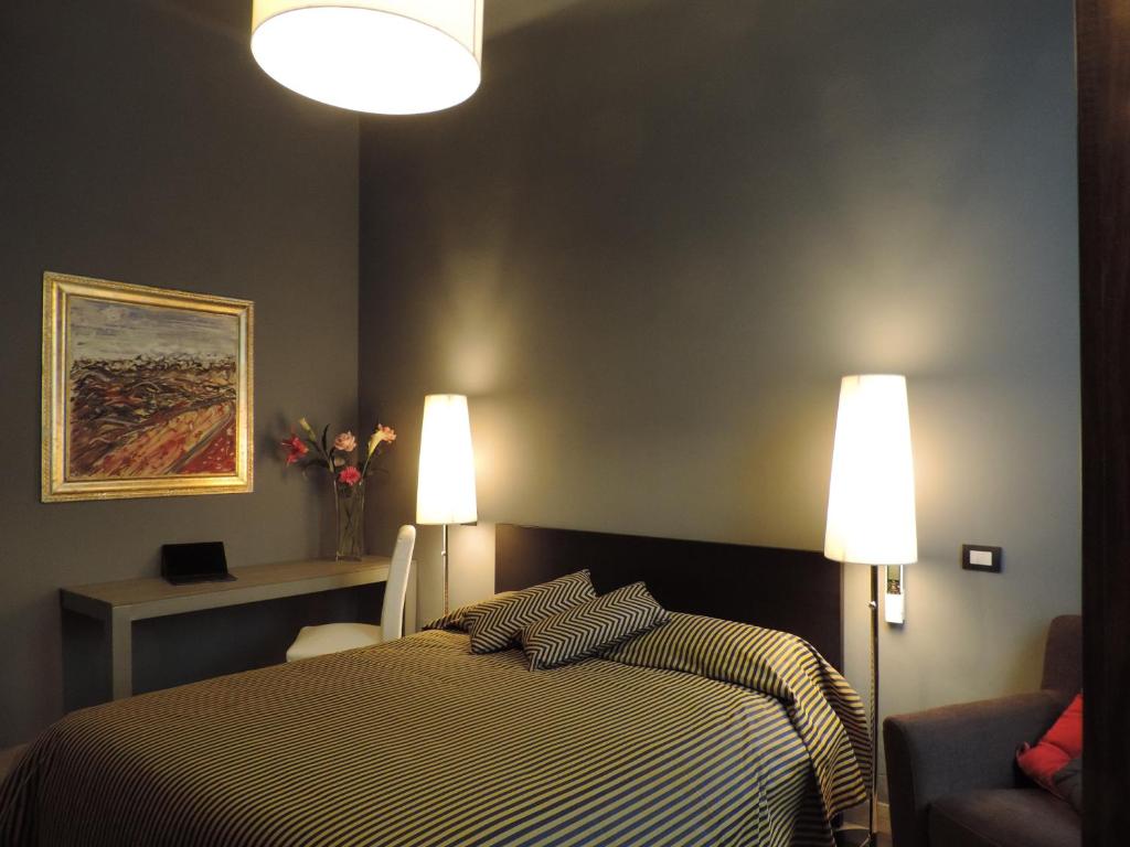 ピサにあるCorridoni Suitesのベッドルーム1室(ベッド1台、ランプ2つ、椅子付)