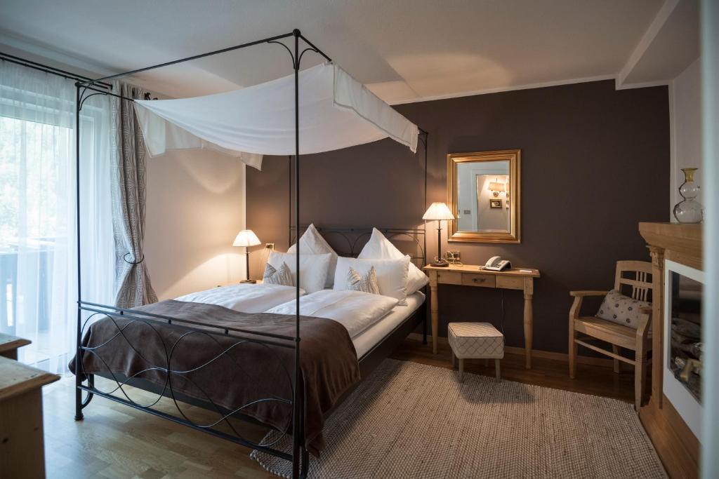 a bedroom with a bed, a chair, and a lamp at Chalet Hotel Hartmann - Adults Only in Ortisei