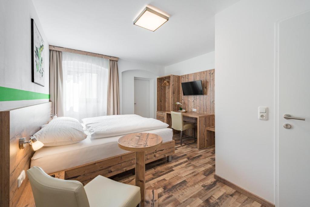 a bedroom with a bed and a table and a desk at City Rooms Wels - contactless check-in in Wels
