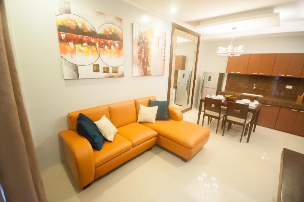 ein Wohnzimmer mit einem orangenen Sofa und einer Küche in der Unterkunft NF Suites in Davao City