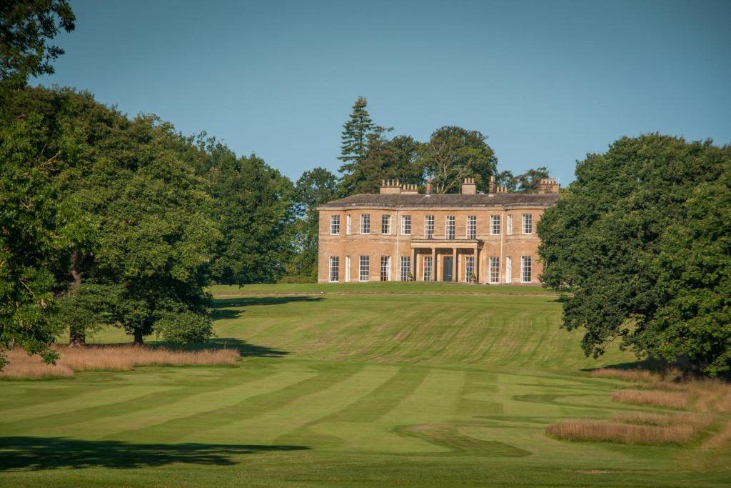 a large house on a green field with trees at Rudding Park in Harrogate