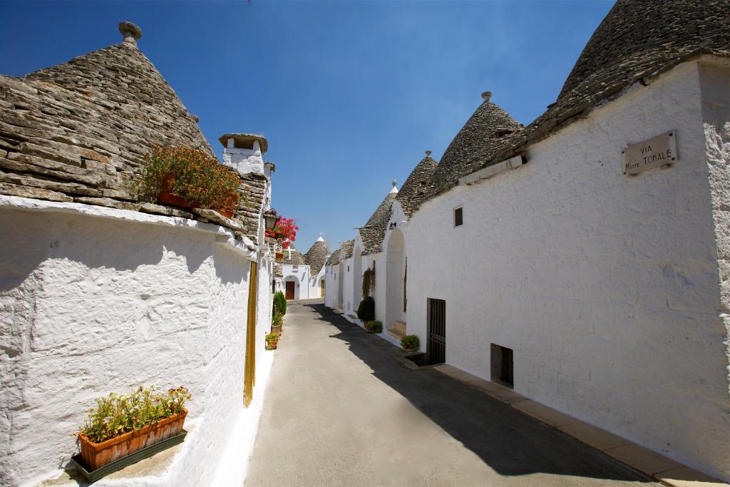 een steegje met witte gebouwen en potplanten bij Trulli e Puglia Resort in Alberobello