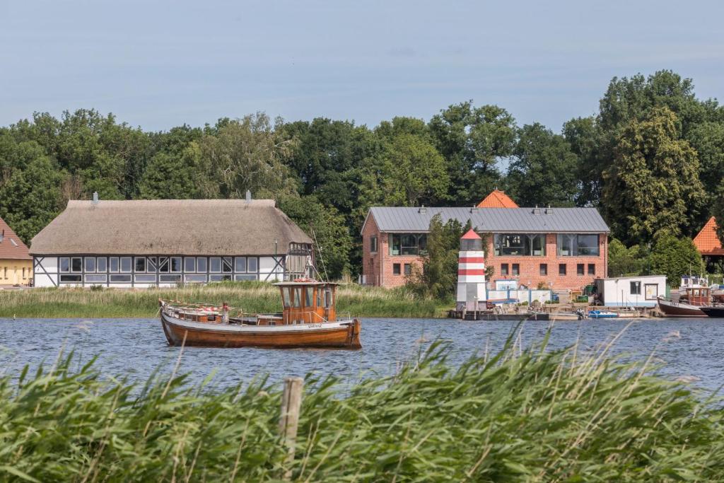 a small boat in the water in front of buildings at Alte Scheune am Focker Strom in Mursewiek