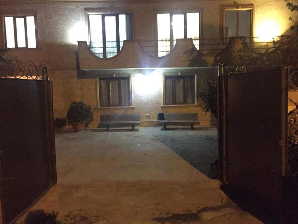 an open gate to a building with two benches at Cico Guest House in Batumi