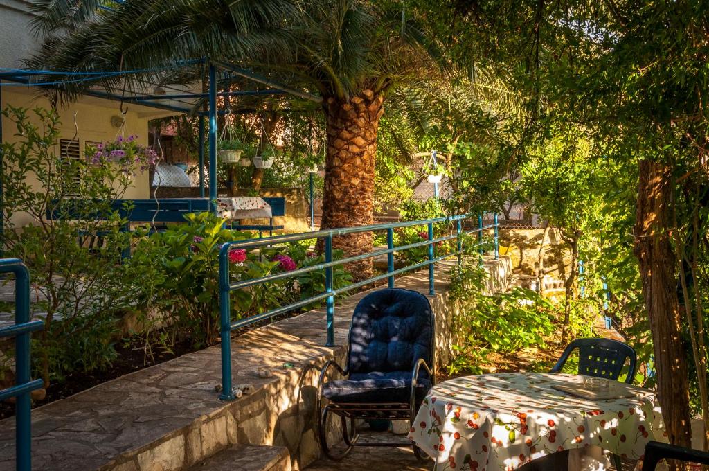 una mesa y sillas en un jardín con una palmera en Apartments Villa Petranović, en Budva