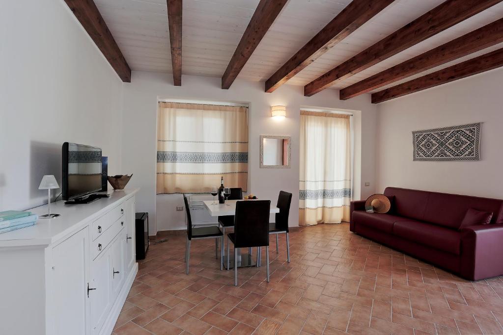 een woonkamer met een rode bank en een tafel bij Agriturismo Casale Degli Ulivi Alghero in Santa Maria la Palma