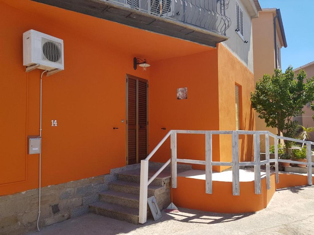 un edificio naranja con escaleras y una escalera en B&B Le Peonie, en Badesi