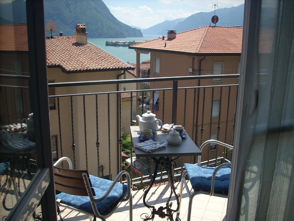 balcón con mesa, sillas y vistas al agua en Casa Vacanze Valvendra en Lovere