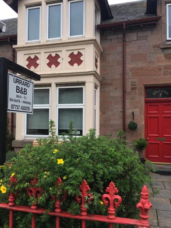 a red fence in front of a house with a red door at Urrard B&B in Dingwall