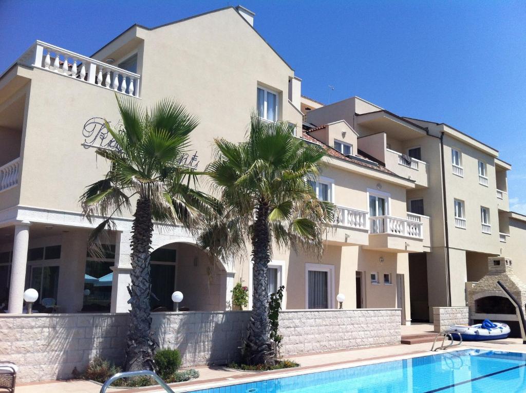 um edifício com palmeiras em frente a uma piscina em Villa Kastel em Povljana