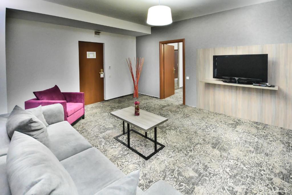 Hotel Europeca في كرايوفا: غرفة معيشة مع أريكة بيضاء وتلفزيون