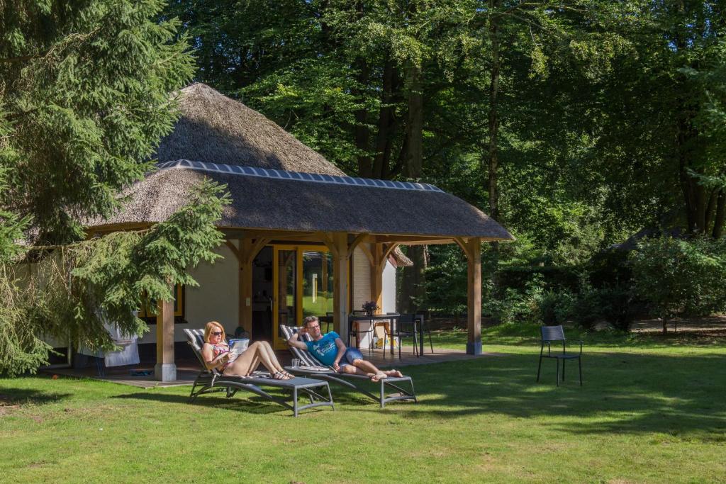 dos personas sentadas en sillas frente a una casa en Molecaten Park De Leemkule, en Hattem