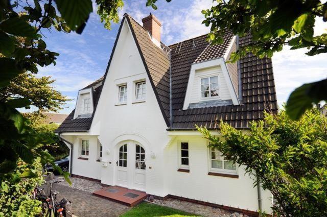 a large white house with a black roof at Appartment Düne in Westerland