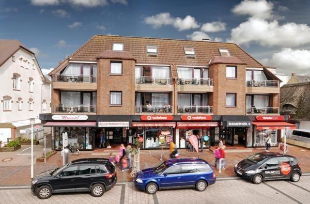 eine Gruppe von Autos, die vor einem Gebäude geparkt sind in der Unterkunft Sylter Besserburg App. 2P in Westerland