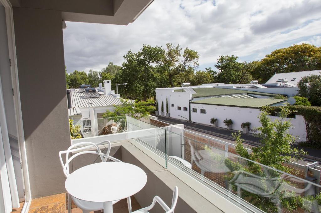 a balcony with a white table and chairs and a view at Laanhof Studios in Stellenbosch