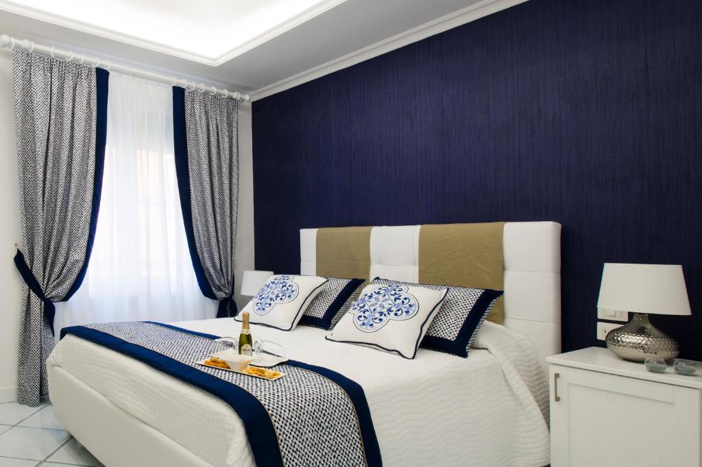 a bedroom with a white bed with blue and white pillows at B&B Maiori Luxury in Maiori