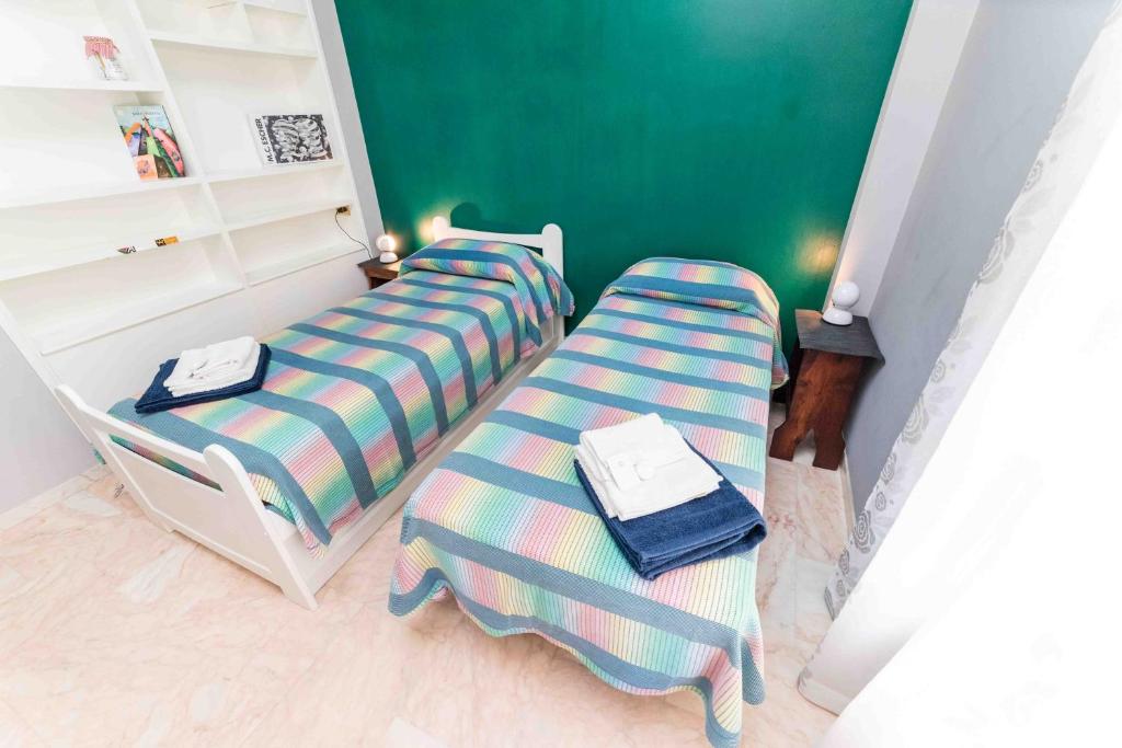 two beds in a room with a green wall at Casa Mare e Monti Castelbuono in Castelbuono