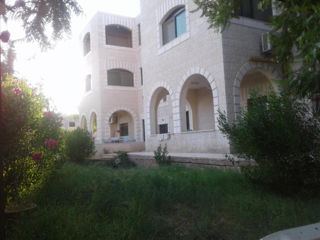 un grand bâtiment en briques avec une cour herbeuse devant lui dans l'établissement Jericho Waleed's Hostel, à Jéricho