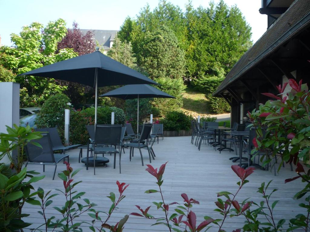 a patio with tables and chairs and umbrellas at Best Western Plus Hostellerie Du Vallon in Trouville-sur-Mer