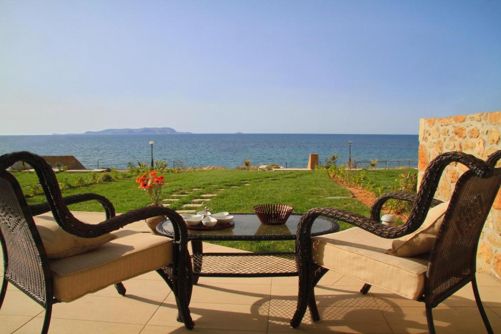 un patio con 2 sillas, una mesa y el océano en Sea View Beachfront Villa Maria, en Gouves