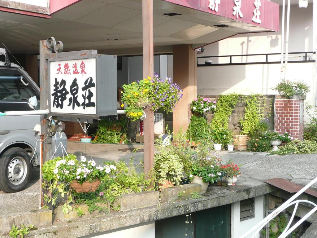 una señal frente a un edificio con plantas y flores en Seisenso, en Nozawa Onsen