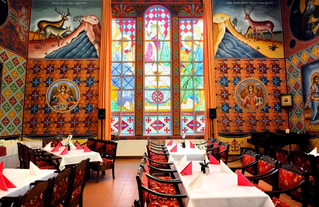 イーサルミにあるHotel Golden Dome Iisalmiのテーブルと椅子、ステンドグラスの窓が備わるレストラン