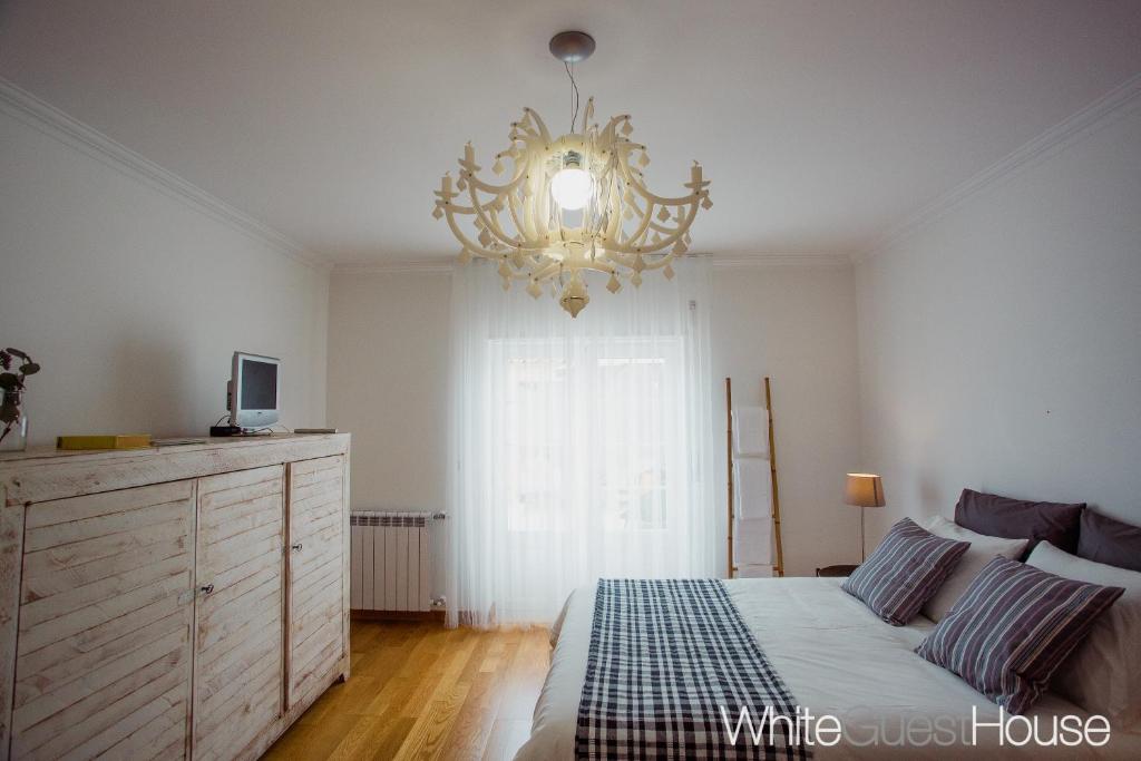 a bedroom with a bed and a chandelier at White Guest House in Peniche