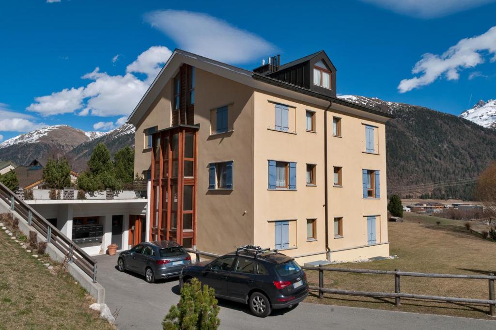 un edificio con dos coches estacionados frente a él en Chesa Roser - Samedan, en Samedan