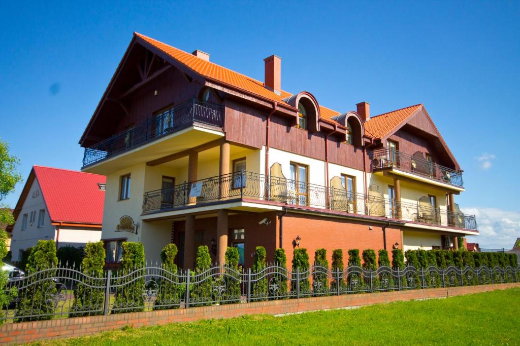 una casa grande con una valla delante en Villa Tropikana en Łeba