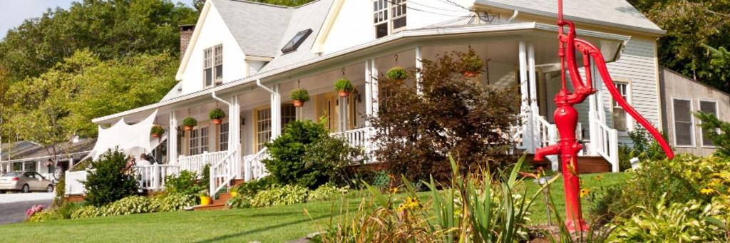 a large white house with flowers in front of it at Mount Battie Inn in Lincolnville