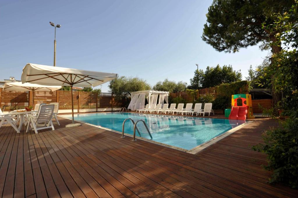 a swimming pool with chairs and a table and an umbrella at Bellariva Feeling Hotel in Rimini