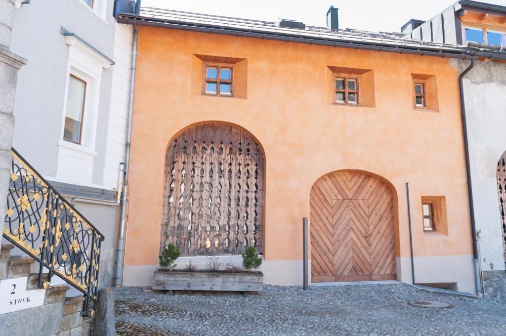 ein orangefarbenes Gebäude mit zwei großen Holztüren in der Unterkunft Alte Scheune - Samedan in Samedan